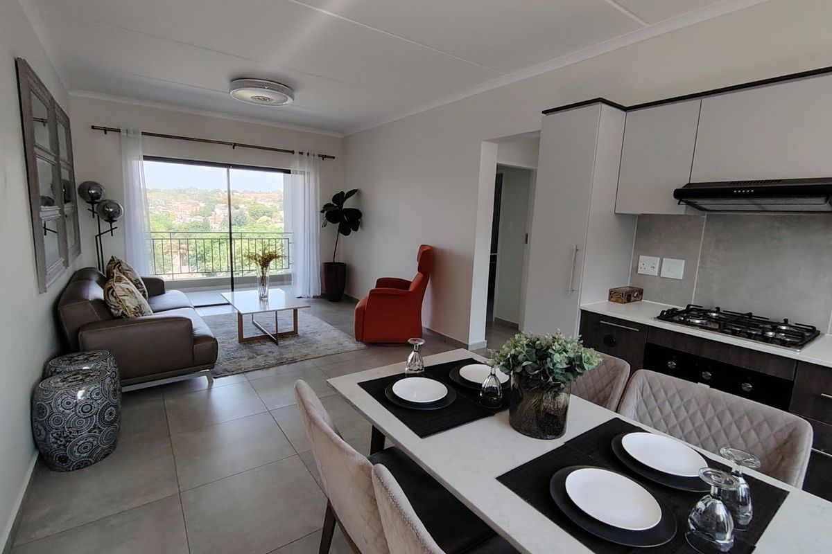 Modern open-plan living and dining area featuring a well-equipped kitchen with gas hob, sleek cabinetry, and direct access to a balcony with scenic views.