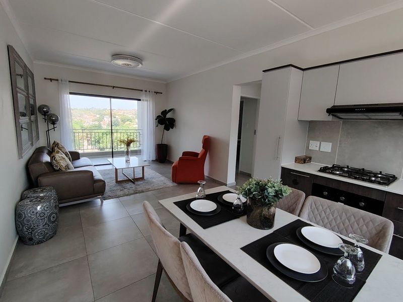 Modern open-plan living and dining area featuring a well-equipped kitchen with gas hob, sleek cabinetry, and direct access to a balcony with scenic views.