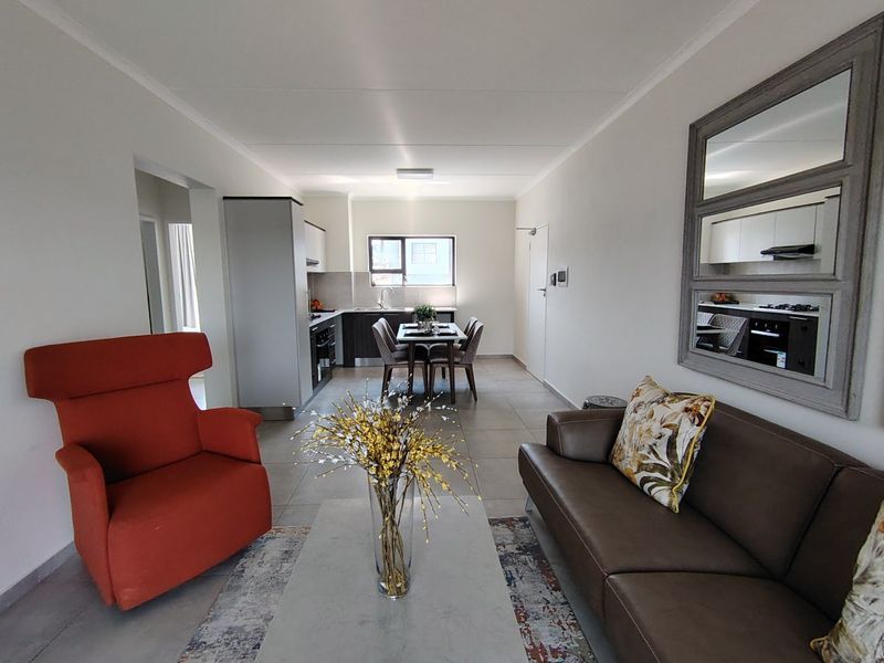 An open-plan living and dining area featuring tiled floors, a modern kitchen with built-in appliances, and a bright, functional layout.