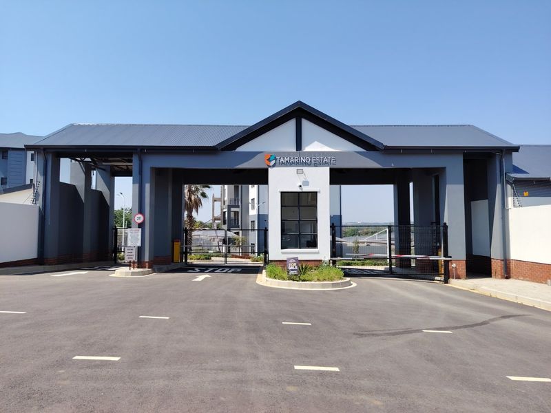 The main entrance gatehouse of Tamarino Estate, featuring a modern security structure, automated boom gates, and paved driveway access.