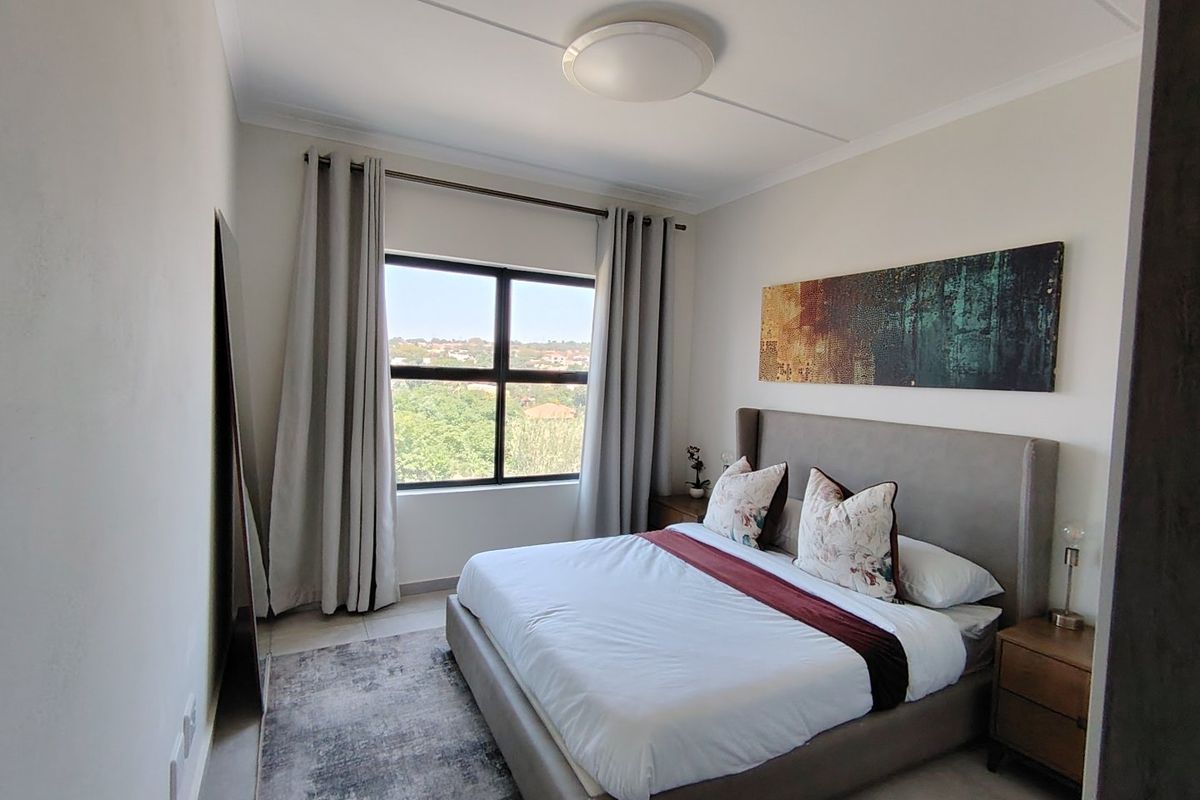 A well-maintained bedroom featuring neutral walls, tiled flooring, a central ceiling light, and a window providing natural light and an elevated view.