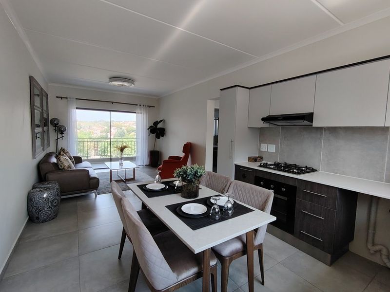Modern open-plan living area featuring a contemporary kitchen with built-in appliances, tiled floors, and direct access to a balcony with scenic views.