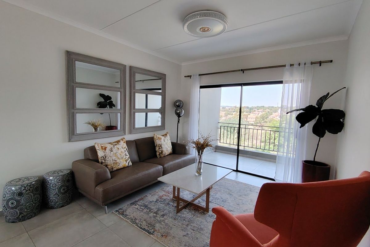 A bright and well-maintained living room featuring tiled floors, a modern ceiling light, and large sliding glass doors leading to a balcony with scenic views.