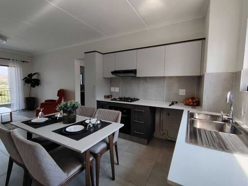 Modern open-plan kitchen and dining area featuring sleek cabinetry, gas hob, integrated oven, and stainless steel sink with tiled finishes throughout.