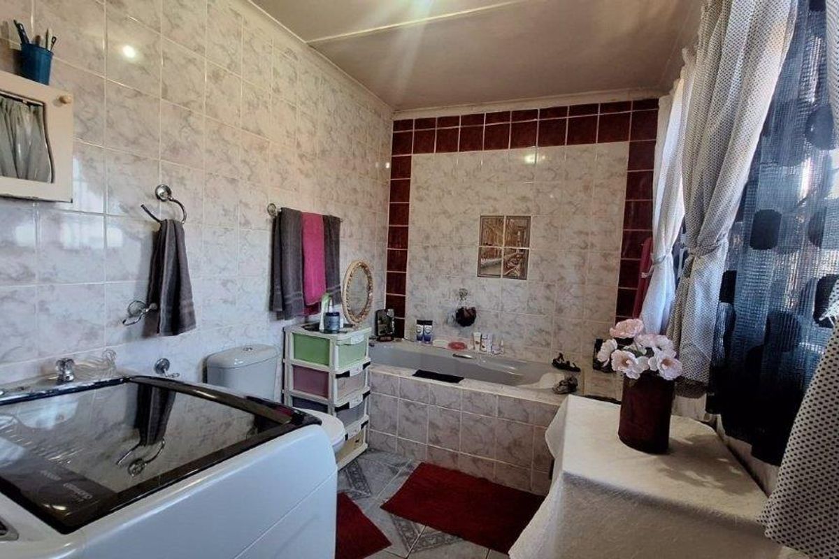 A functional bathroom featuring a built-in bathtub and tiled finishes, offering potential for modernization and aesthetic updates to improve the overall space.