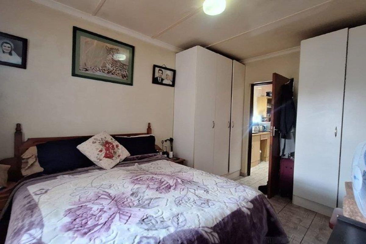 A functional bedroom featuring built-in cupboards and tiled flooring, providing practical storage and a neutral foundation for personal styling.