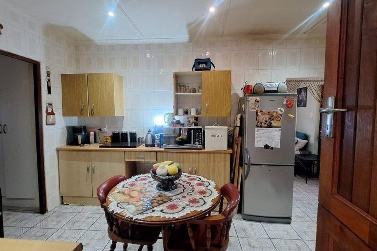 A functional kitchen featuring laminate cabinetry, tiled splashbacks, and tiled flooring, providing a practical workspace with integrated storage solutions.