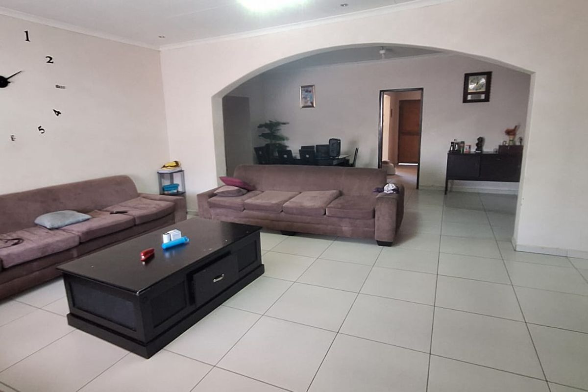 Spacious living area featuring neutral tiled flooring and a distinctive arched architectural opening leading to an adjacent room.