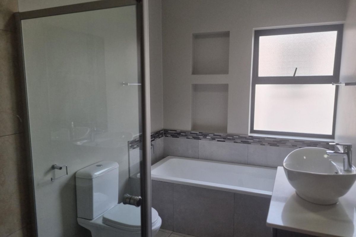 Modern bathroom featuring a glass-enclosed shower, a built-in bathtub with tiled surround, a vessel sink vanity, and built-in wall niches.