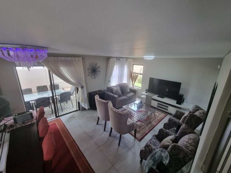 Spacious open-plan living and dining area featuring tiled flooring, modern lighting, and large sliding glass doors providing seamless access to the outdoor patio.