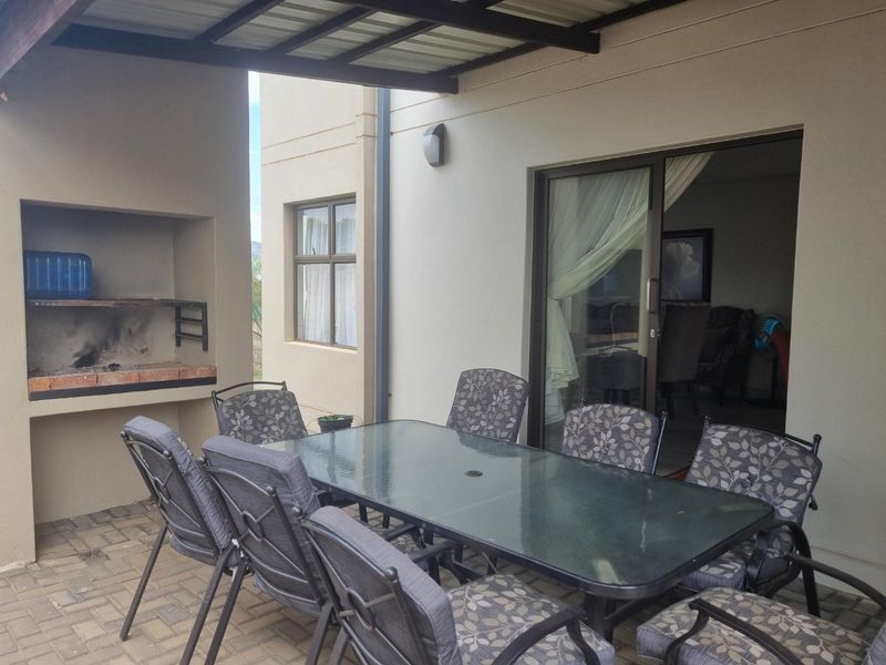 A covered patio area featuring a built-in braai, paved flooring, and direct access to the interior living space through a sliding glass door.