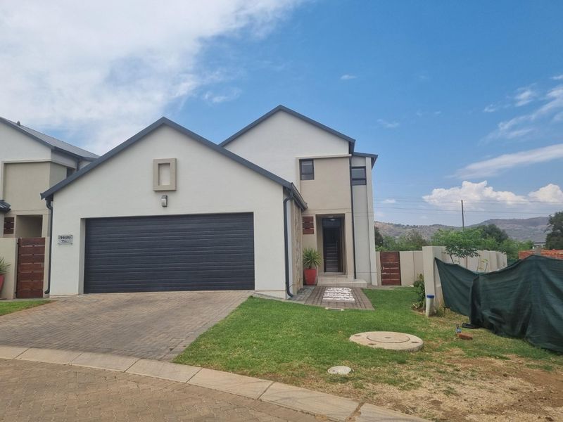 Front elevation of a modern double-story house featuring a double garage, paved driveway, and established boundary walls.