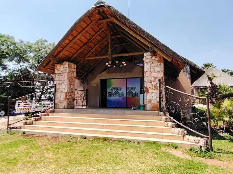 Front elevation of a commercial building featuring a prominent thatched roof, stone-clad pillars, and tiled entrance steps with decorative wrought iron railings.