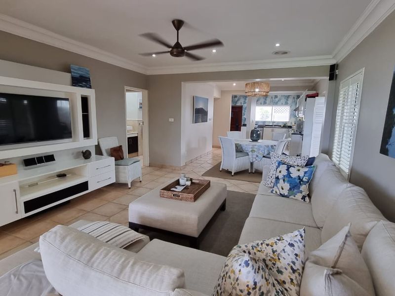 Open-plan living and dining area featuring tiled flooring, a built-in media unit, and a seamless flow into the adjacent kitchen space.