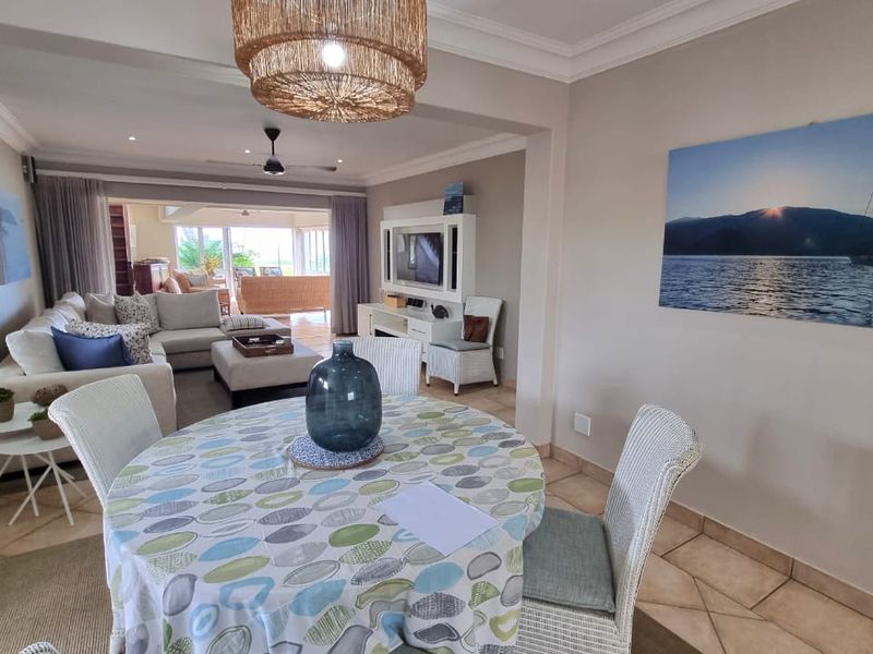 Open-plan living and dining area featuring tiled flooring, recessed ceiling lighting, and seamless flow to an adjoining patio space.