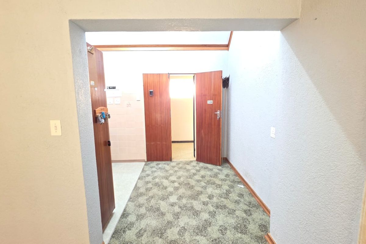 A functional hallway area featuring carpeted flooring and wooden door frames, providing access to adjacent rooms within the apartment.