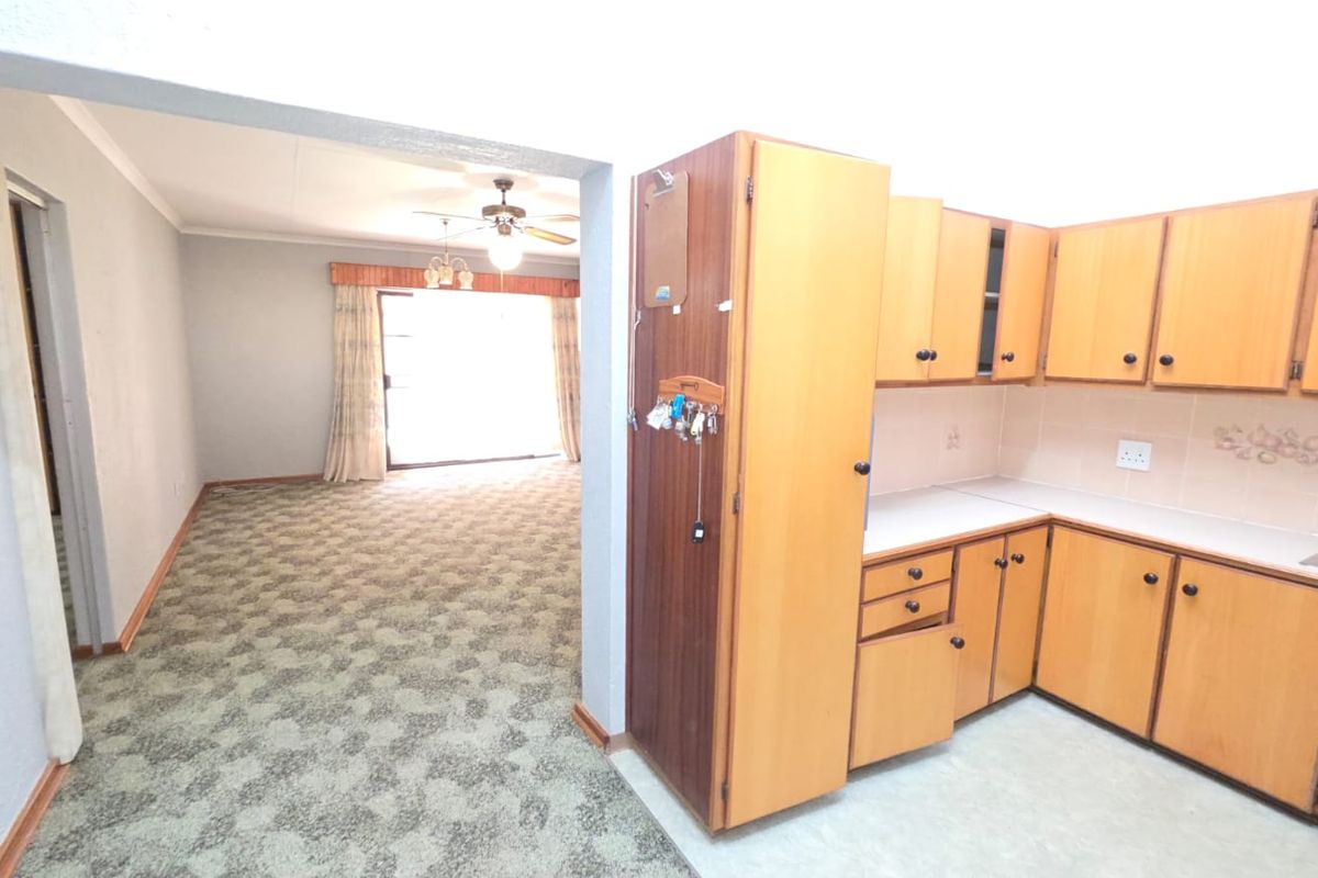 Open plan living area featuring a functional kitchen with laminate cabinetry and a spacious lounge area with access to a balcony through sliding doors.
