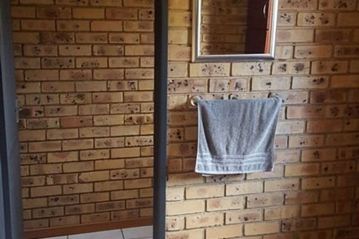 A functional bathroom space featuring exposed brick walls and neutral ceramic floor tiling, providing a rustic aesthetic ready for modern updates.