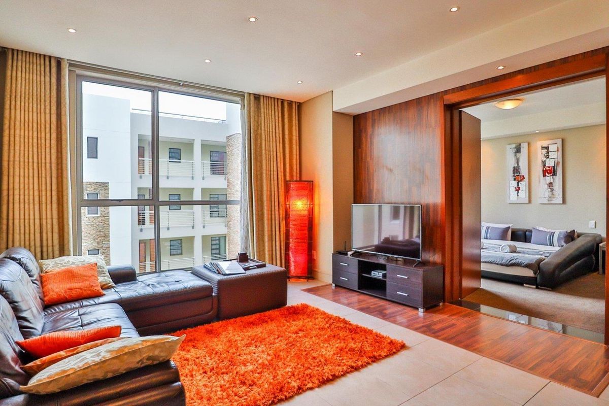 Modern living room featuring large floor-to-ceiling windows, recessed downlighting, and elegant wood veneer wall paneling with seamless transitions between tiled and hardwood flooring.