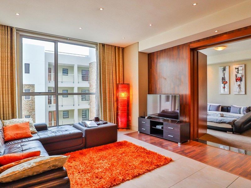 Modern living room featuring large floor-to-ceiling windows, recessed downlighting, and elegant wood veneer wall paneling with seamless transitions between tiled and hardwood flooring.