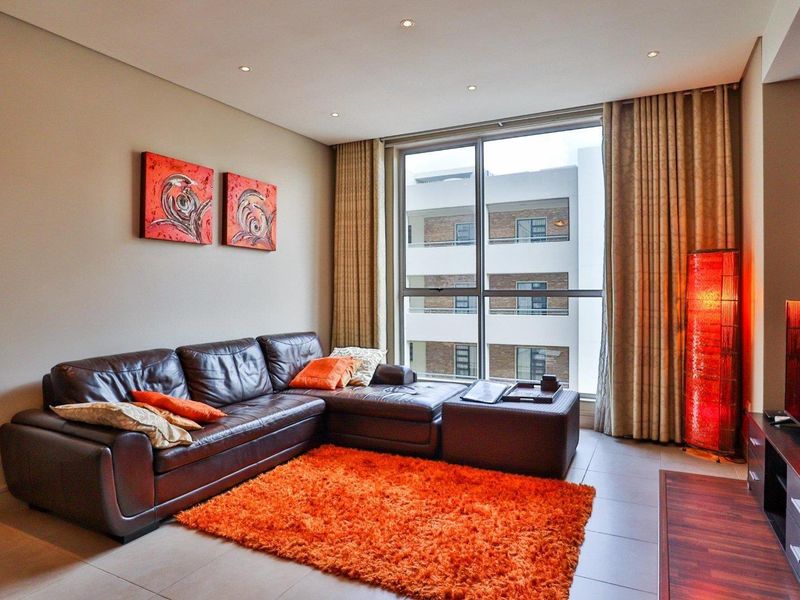 A well-maintained living room featuring tiled flooring, recessed downlighting, and a large sliding glass door providing natural light and access to the exterior.