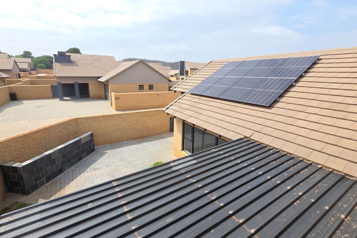 Elevated view of the property exterior featuring a tiled roof with installed solar panels and a paved courtyard area.