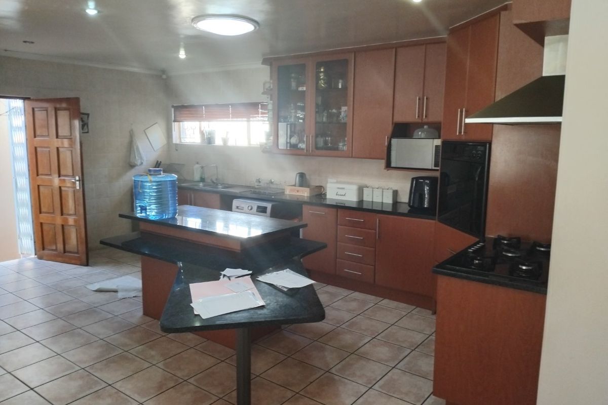 Spacious kitchen featuring wooden cabinetry, granite countertops, built-in oven, gas hob, and tiled flooring, offering a functional layout for cooking and preparation.