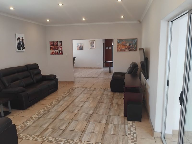 Spacious living room featuring tiled flooring with decorative border inlay, recessed downlighting, and access to an outdoor area via a sliding glass door.