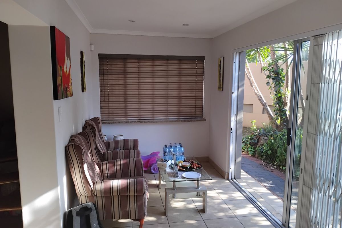 A bright living area featuring tiled flooring, recessed lighting, and a large sliding glass door providing direct access to the garden.