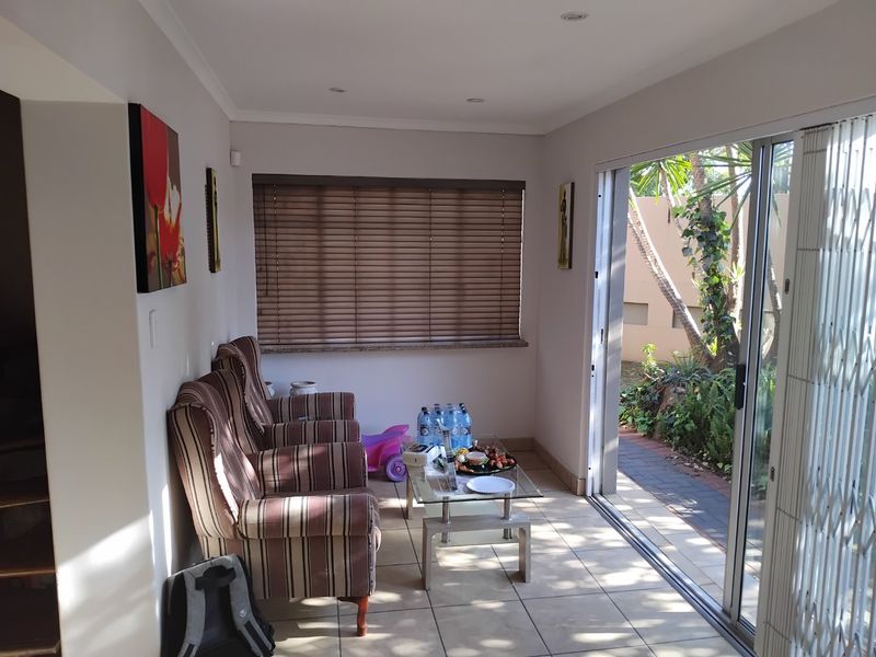 A bright living area featuring tiled flooring, recessed lighting, and a large sliding glass door providing direct access to the garden.