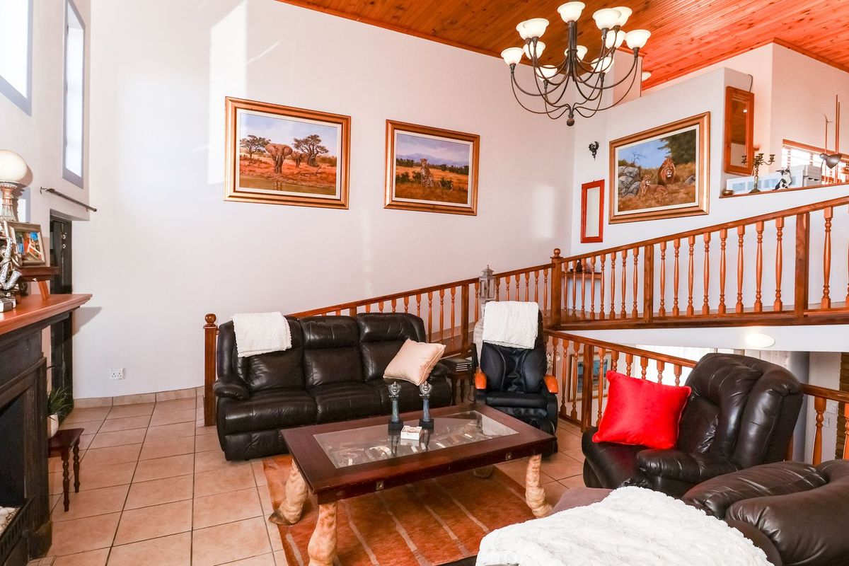 Spacious living room featuring a fireplace, high timber ceilings, and a wooden balustrade overlooking the lower level.
