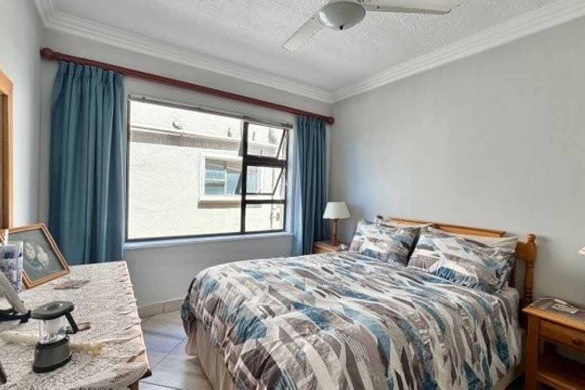 A bedroom featuring tiled flooring, ceiling fan, and cornicing, offering a functional space with natural light.