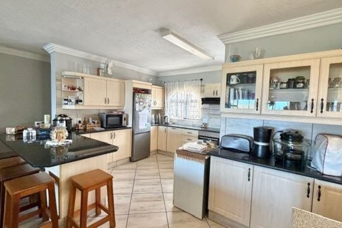 Spacious kitchen featuring granite countertops, ample built-in cabinetry with glass-front displays, and ceramic floor tiling, offering a functional layout for cooking and dining.