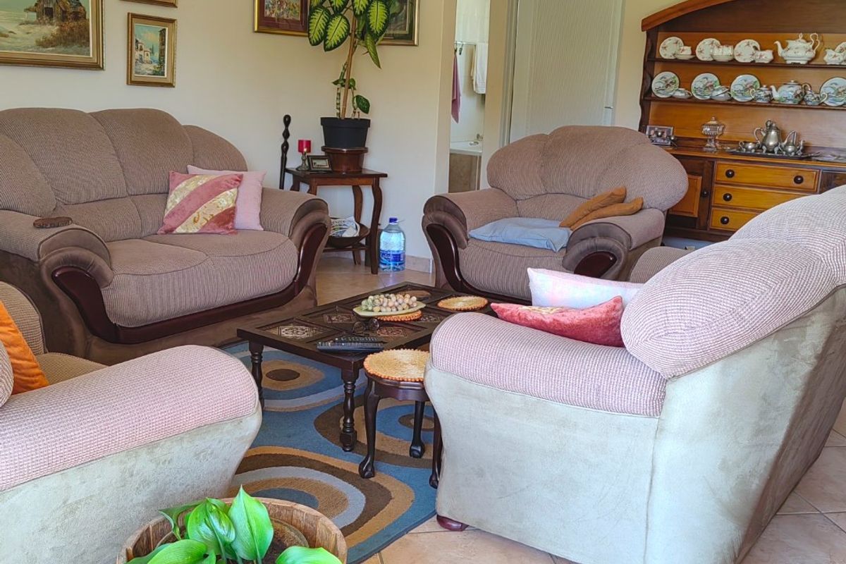 A comfortable living room featuring tiled flooring, coved cornicing, and a ceiling fan, providing a functional and well-maintained space for relaxation.