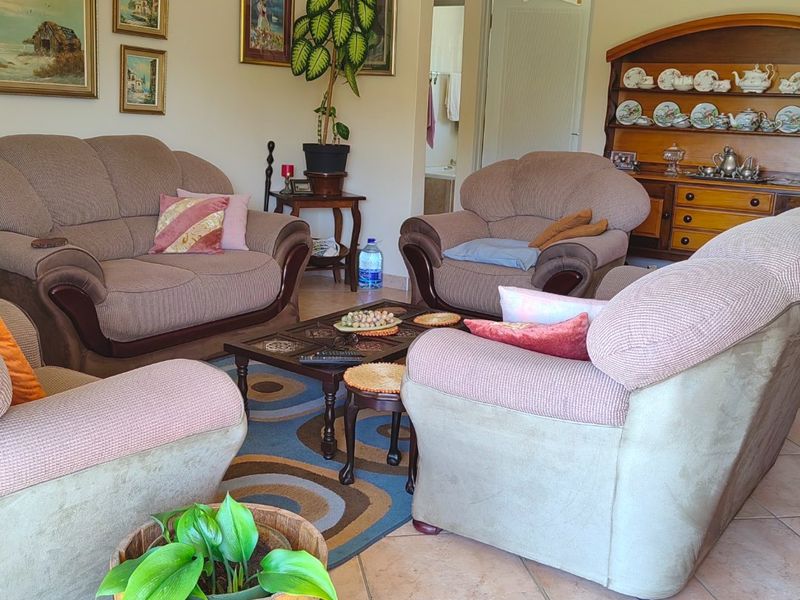 A comfortable living room featuring tiled flooring, coved cornicing, and a ceiling fan, providing a functional and well-maintained space for relaxation.