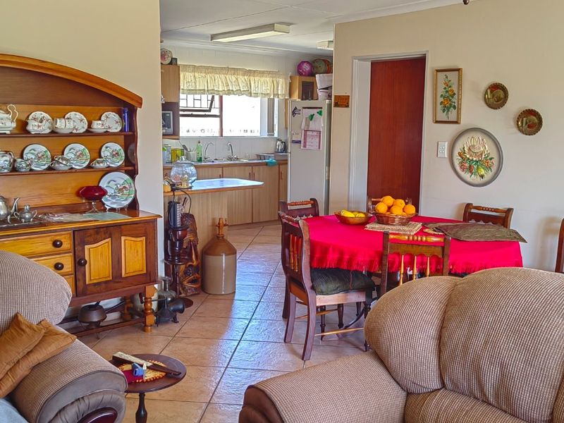Open plan living and dining area featuring tiled floors and a connected kitchen with built-in cabinetry and a breakfast counter.