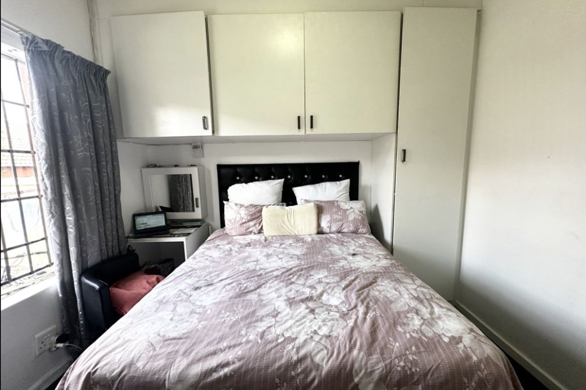 A bedroom featuring built-in overhead and side cabinetry, providing integrated storage solutions alongside a window with security bars.