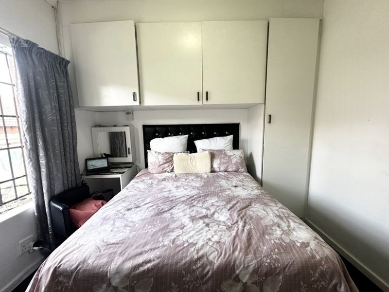 A bedroom featuring built-in overhead and side cabinetry, providing integrated storage solutions alongside a window with security bars.
