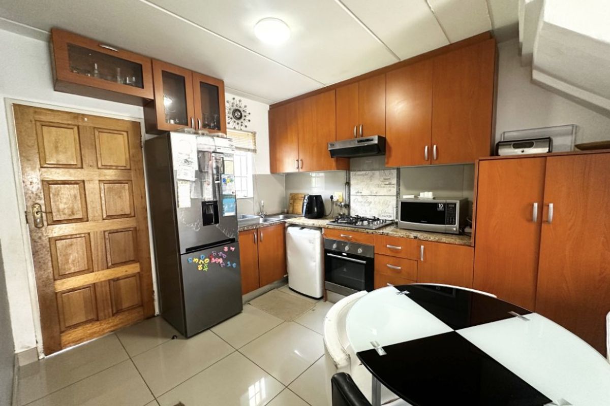 A functional kitchen featuring wood-finish cabinetry, tiled flooring, and integrated appliances, offering a practical layout for daily cooking and meal preparation.