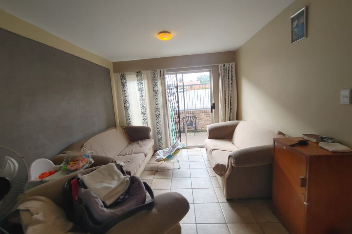 A living room featuring tiled flooring and a sliding glass door providing access to an outdoor patio area.