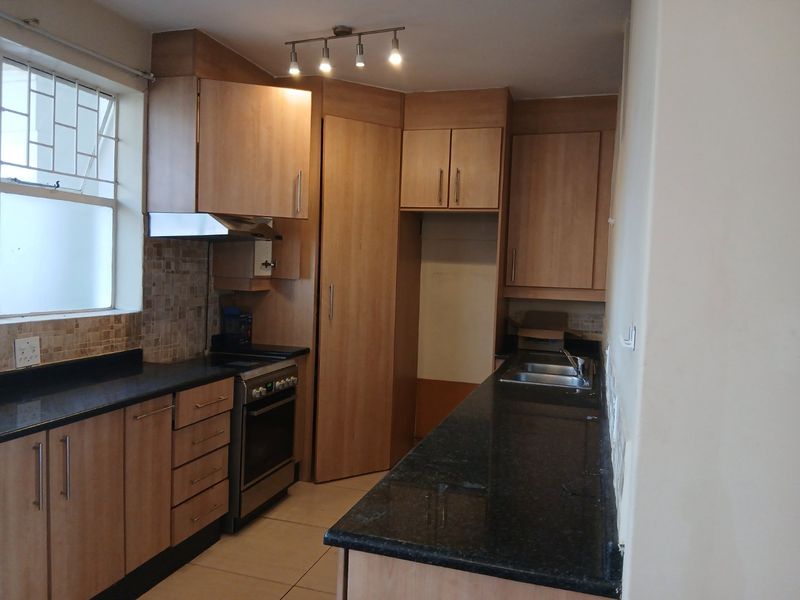 Functional kitchen featuring laminate cabinetry, granite countertops, stainless steel oven, and double bowl sink with tiled backsplash and flooring.