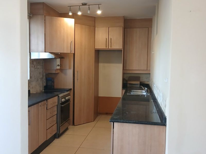 A functional kitchen featuring light wood cabinetry, granite countertops, a built-in oven, and tiled flooring, offering a clean and practical workspace.