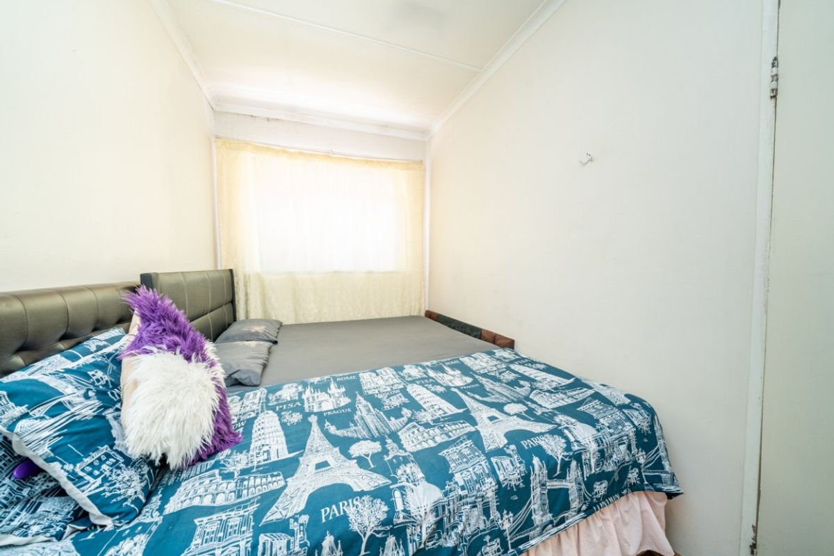 A compact bedroom featuring a window with curtains and standard ceiling coving, requiring cosmetic updates to improve the overall finish.
