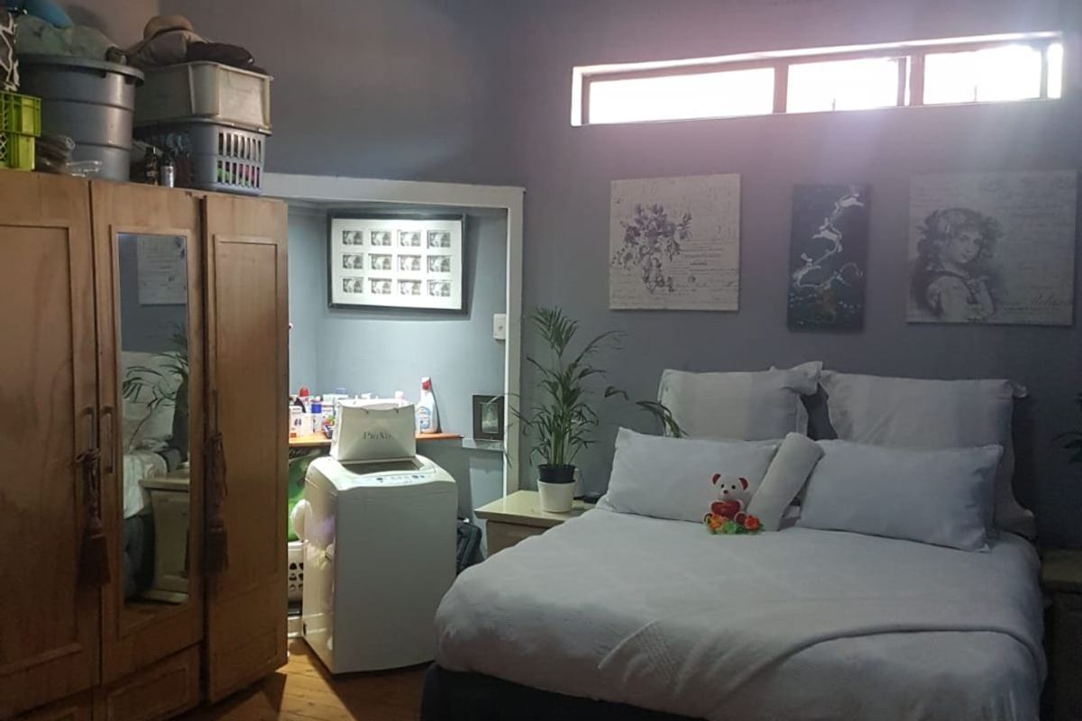 A bedroom featuring exposed beam ceilings, timber flooring, and a built-in alcove area, providing a functional space with natural light from a clerestory window.