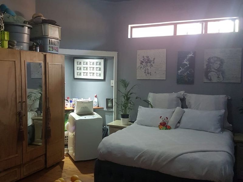 A bedroom featuring exposed beam ceilings, timber flooring, and a built-in alcove area, providing a functional space with natural light from a clerestory window.