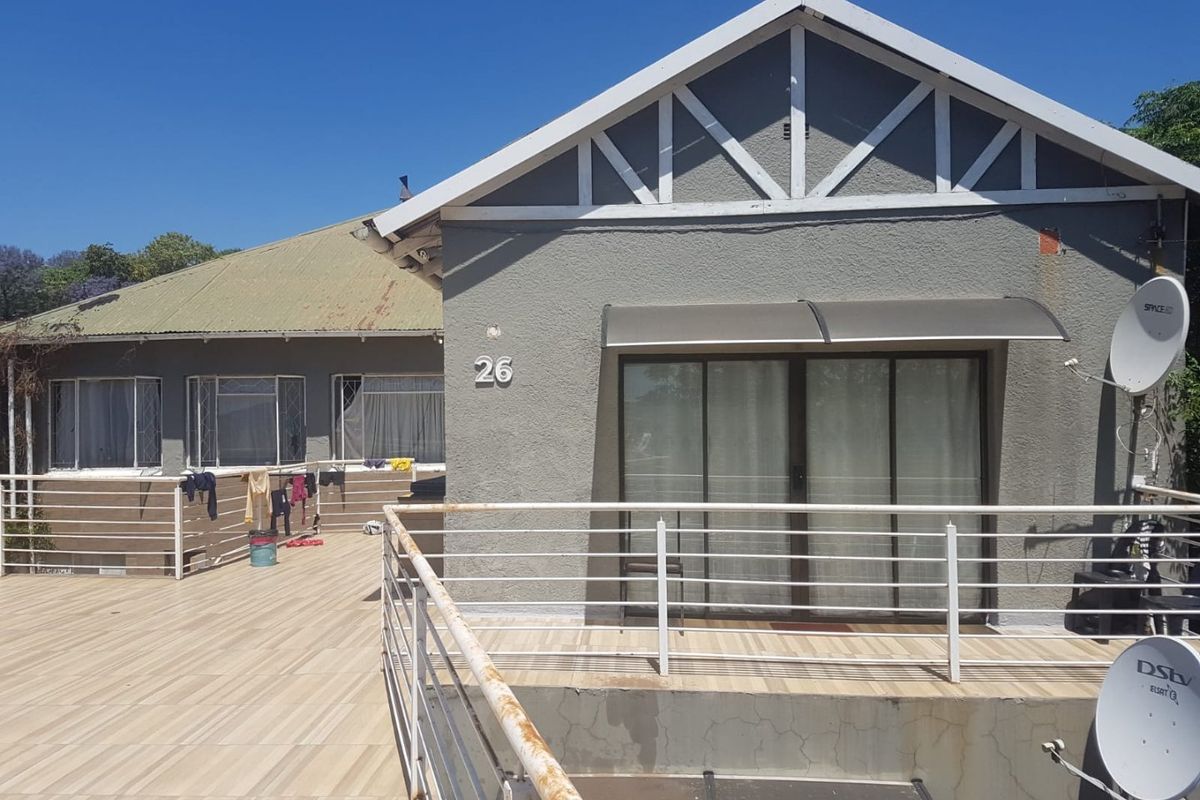 Rear exterior view of the house featuring a tiled patio area, metal balustrades, and sliding glass door access.
