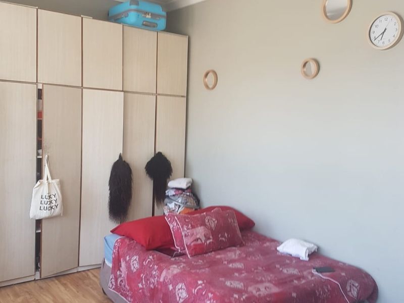 A bedroom featuring built-in cupboards and laminate flooring, with visible water staining on the ceiling.