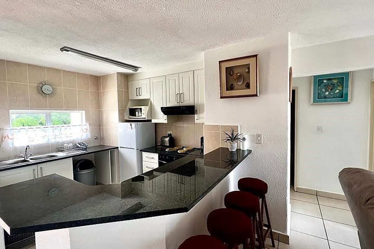 A functional kitchen featuring granite countertops, a breakfast bar, built-in cabinetry, and a tiled backsplash, offering a practical layout for daily use.