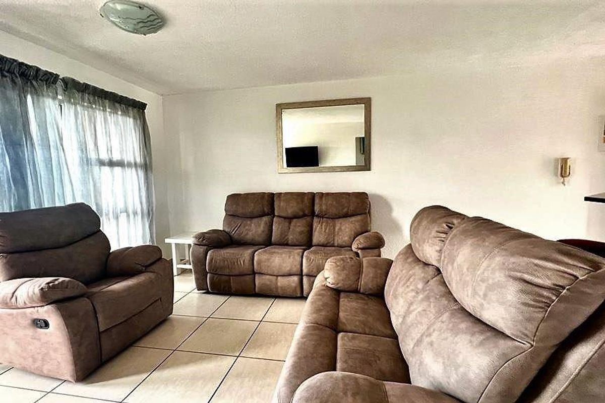 A living room area featuring tiled flooring and a sliding glass door providing natural light.