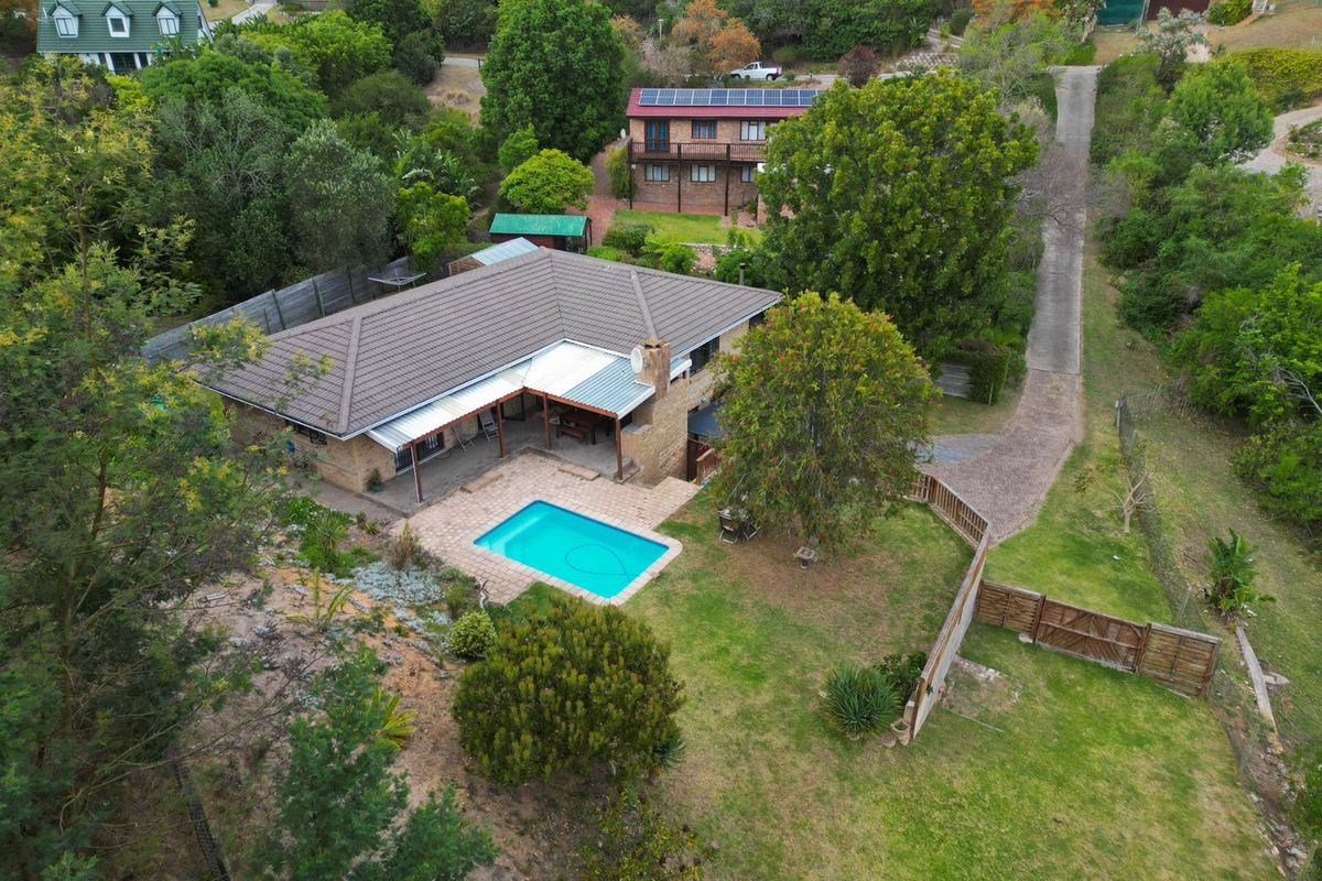 Aerial view of a residential property featuring a swimming pool, covered patio, and established garden set within a spacious, leafy plot.